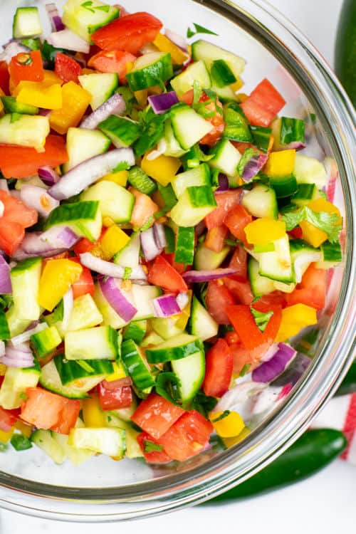 An overhead view of a large glass bowl of cucumber pico de gallo.