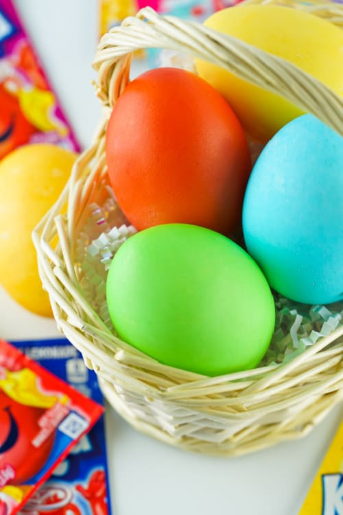 A closeup of a small basket of Kool-Aid dyed Easter eggs.