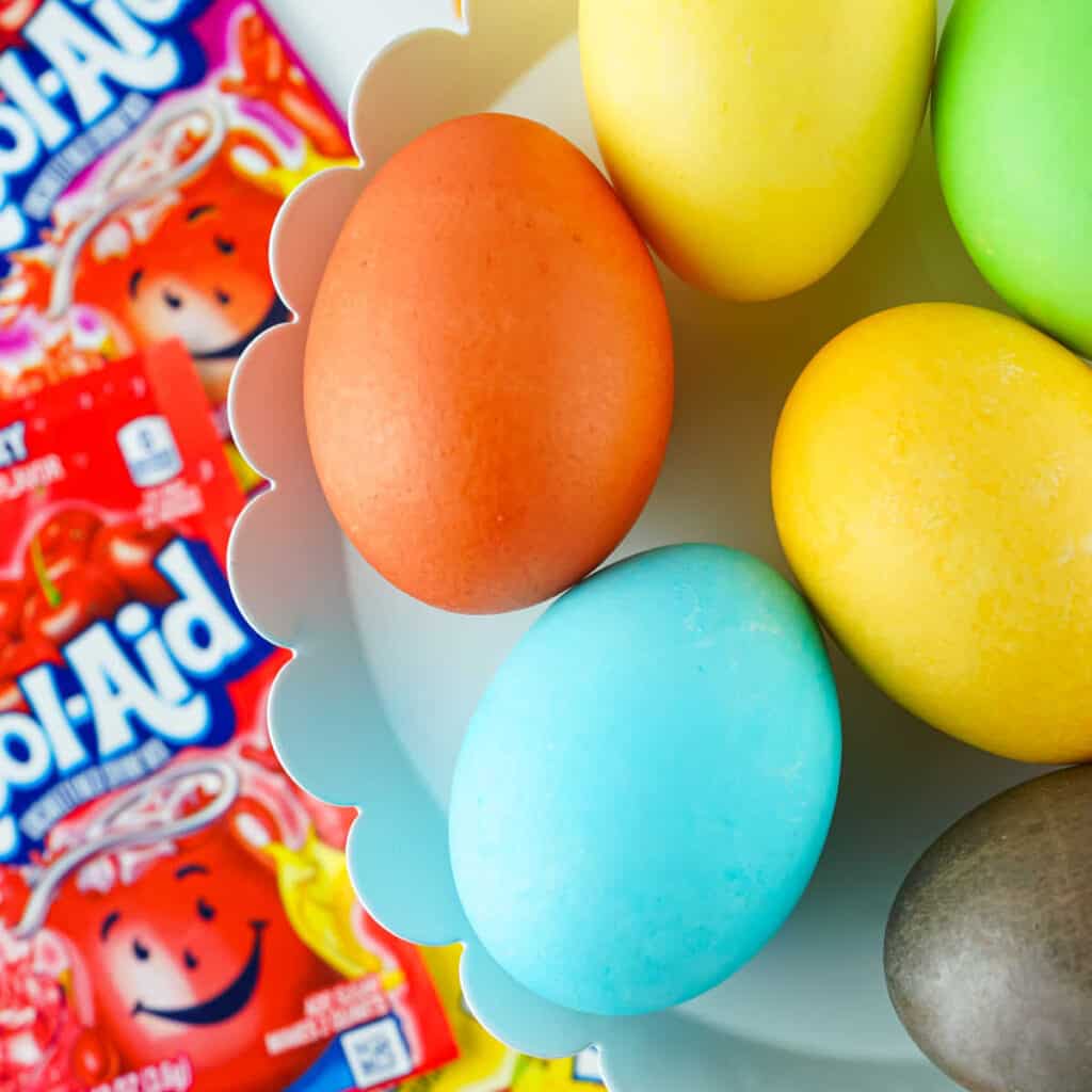 An overhead view of a white dish of Kool-Aid dyed Easter eggs.
