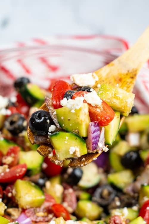 A close-up of a wooden spoon of Mediterranean cucumber salad.