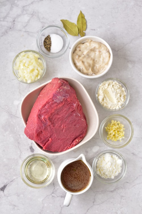 An overhead view of several ingredients for instant pot roast beef and gravy on a white countertop.