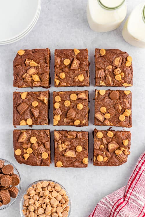 An overhead view of a sheet of peanut butter cup brownies cut into squares.