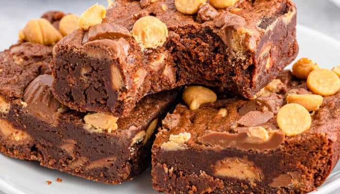 A white plate of peanut butter cup brownies, one with a bite out of it.