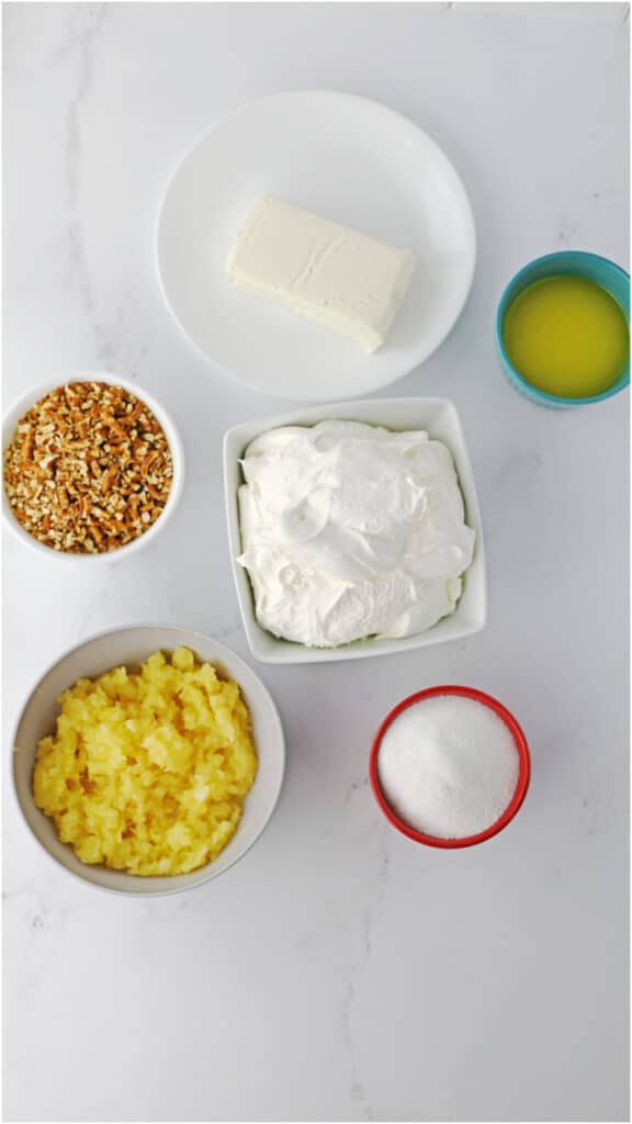 An overhead view of several ingredients for pineapple pretzel fluff on a marble countertop.