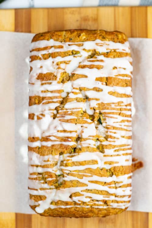An overhead view of a loaf of zucchini bread with pineapple on a sheet of parchment paper.
