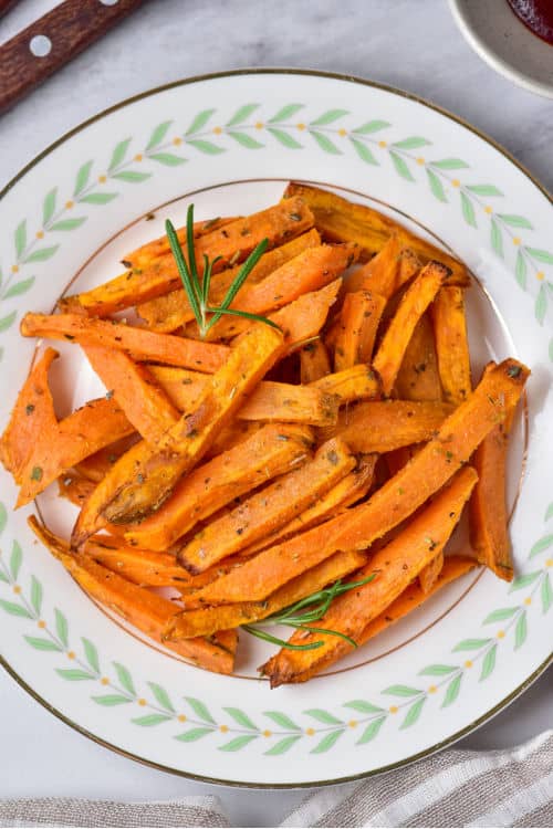 An overhead view of a white plate of air fryer sweet potato fries.