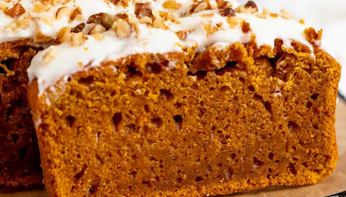 A close-up of a slice of pumpkin bread with cream cheese icing.