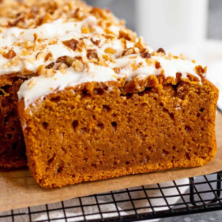 A close-up of a slice of pumpkin bread with cream cheese icing.