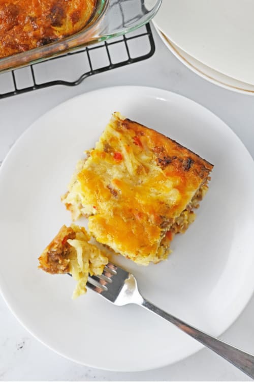 An overhead view of a white plate of bisquick breakfast casserole with a fork on the side.