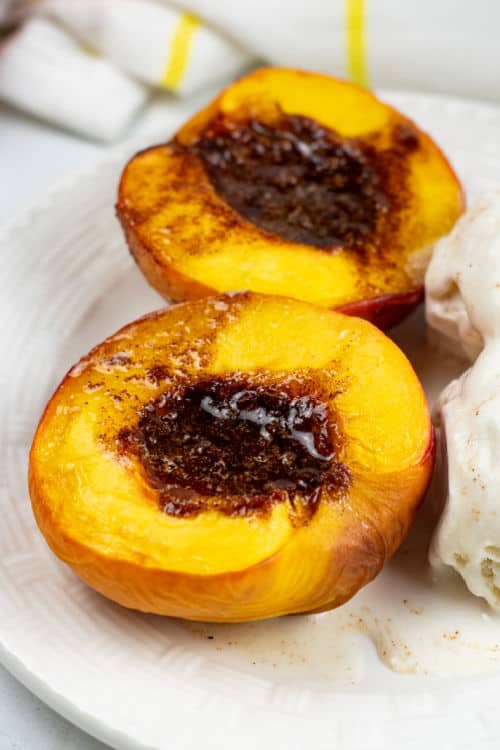 Two air fryer peaches on a white plate