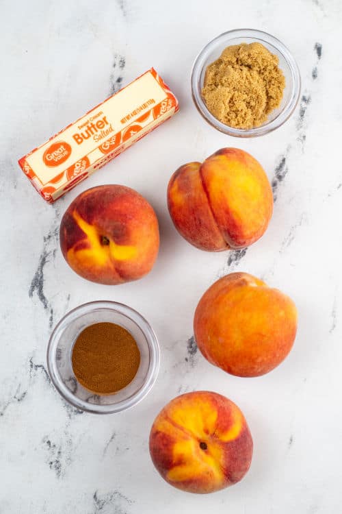 The ingredients for air fryer peaches on a white marble counter top
