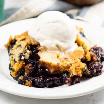 A close up of a plate of blueberry cobbler topped with vanilla ice cream.