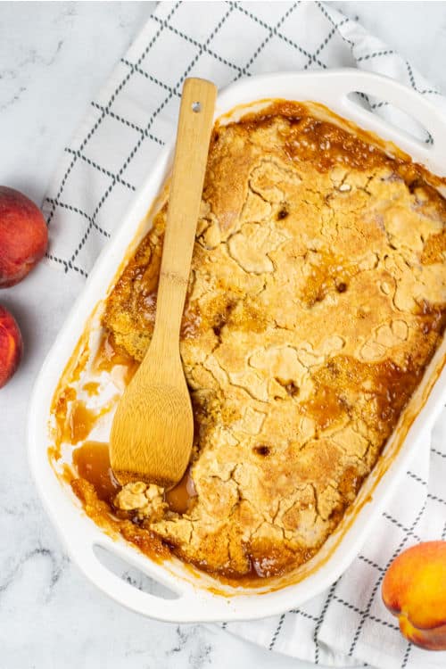 A white baking pan full of peach cobbler made with cake mix