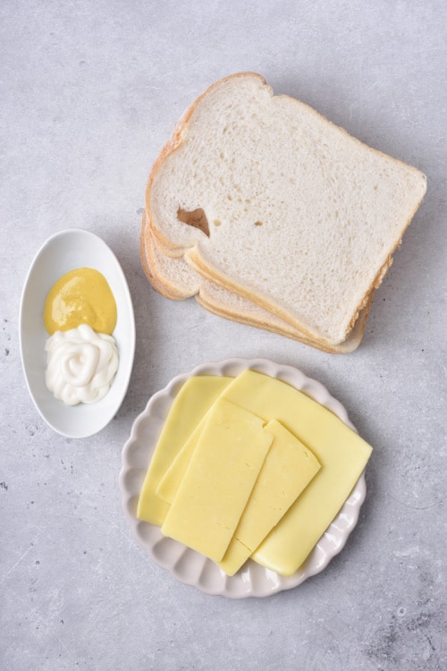 The ingredients for air fryer grilled cheese, sandwich bread, sliced cheese, mayonnaise and mustard