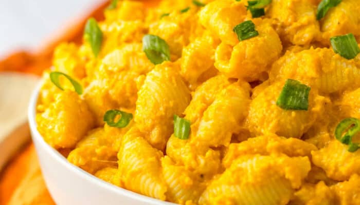 a close up of a side view of a white bowl full of pumpkin mac and cheese