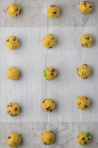 Cookie dough balls on a parchment lined cookie sheet.
