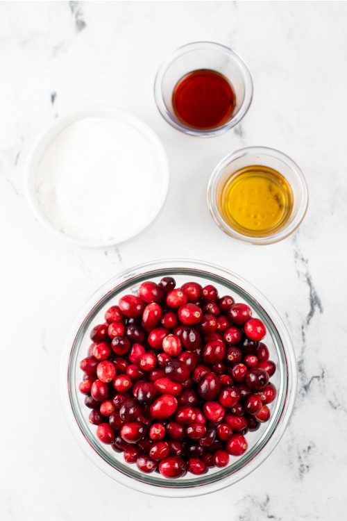 Ingredients for vanilla bourbon cranberry sauce on a white marble counter