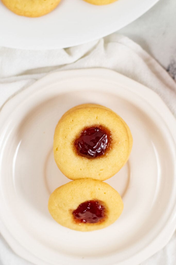 An overhead view of a white plate with a stack of thumbprint cookies.