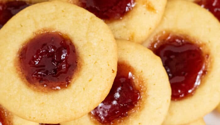 A close up of thumbprint cookies filled with strawberry jam.