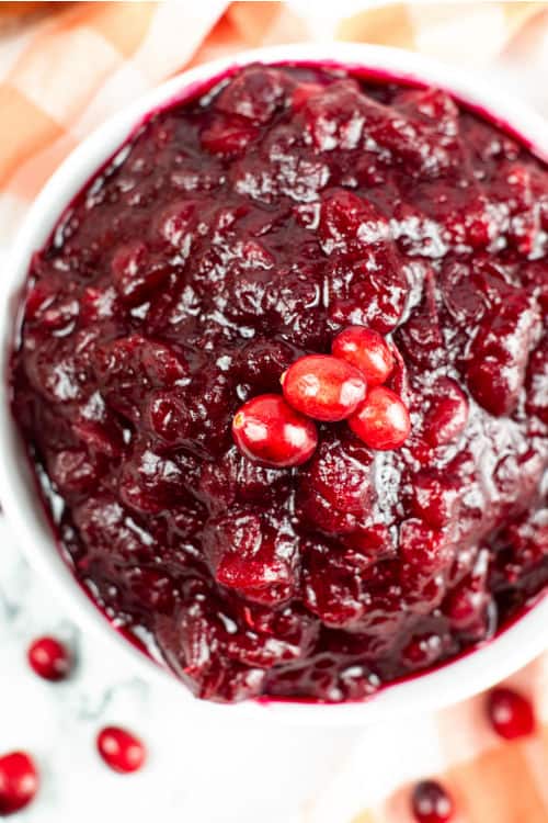 An overhead shot of a white bowl of cranberry sauce