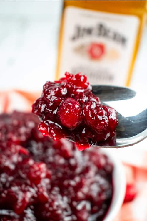 a spoonful of cranberry sauce with a bottle of Jim Bean bourbon in the background