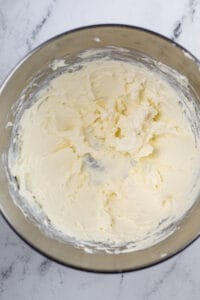 A metal mixing bowl full of creamed cream cheese.