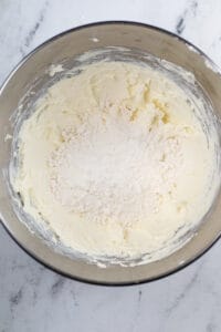 A metal mixing bowl full of creamed cream cheese and dry cake mix.