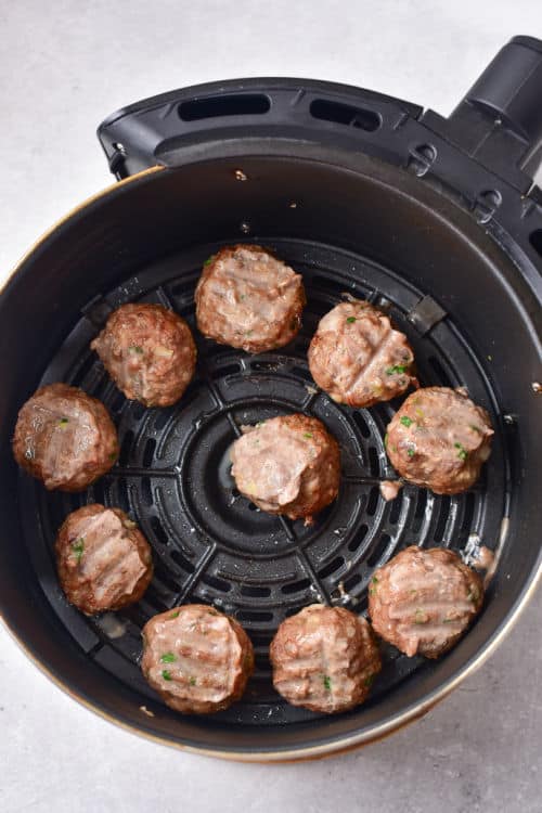 an air fryer basket full of cooked meatballs