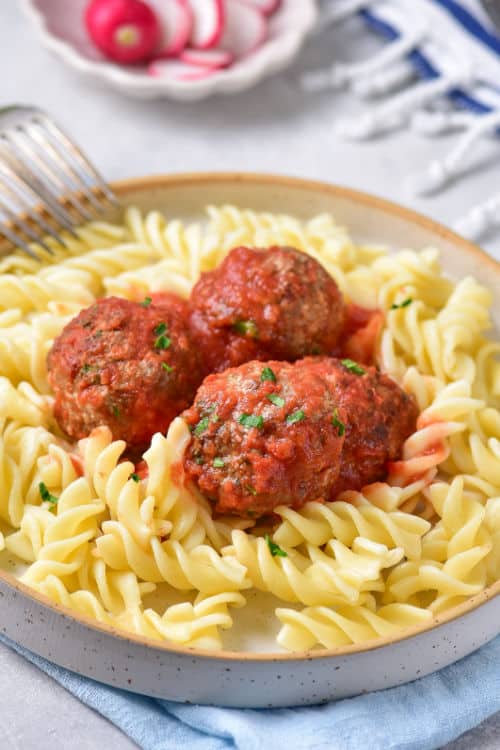 A plate of rotini pasta topped with meatballs