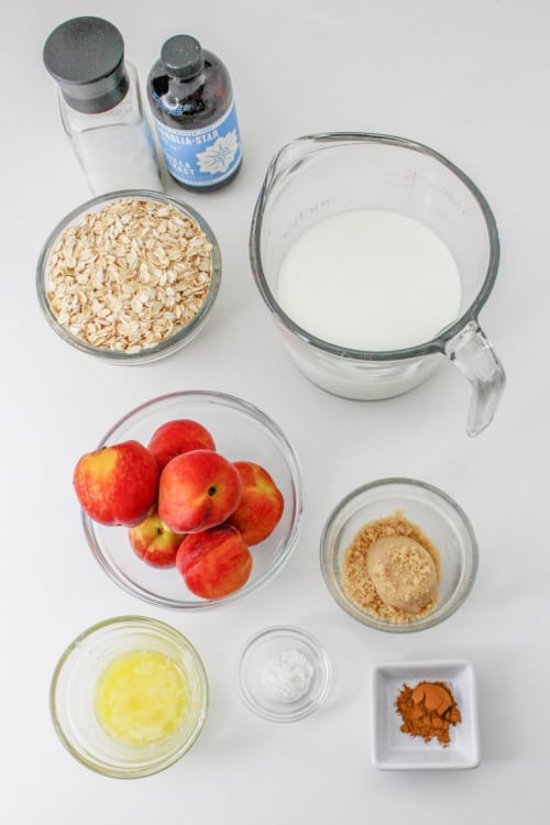 The ingredients for peach baked oatmeal on a white counter top