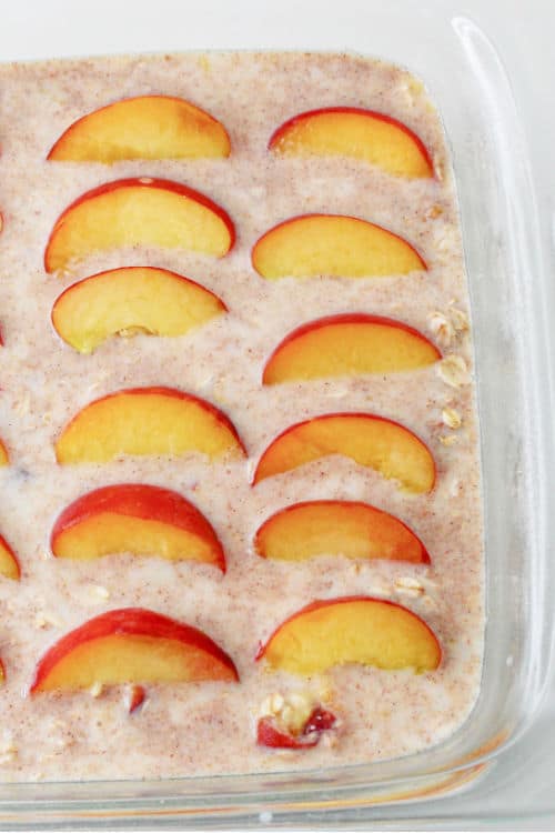 A baking dish full of oatmeal with peach slices on top