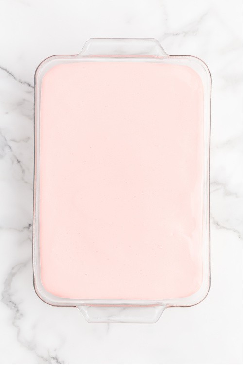a glass baking pan full of a pink creamy mixture