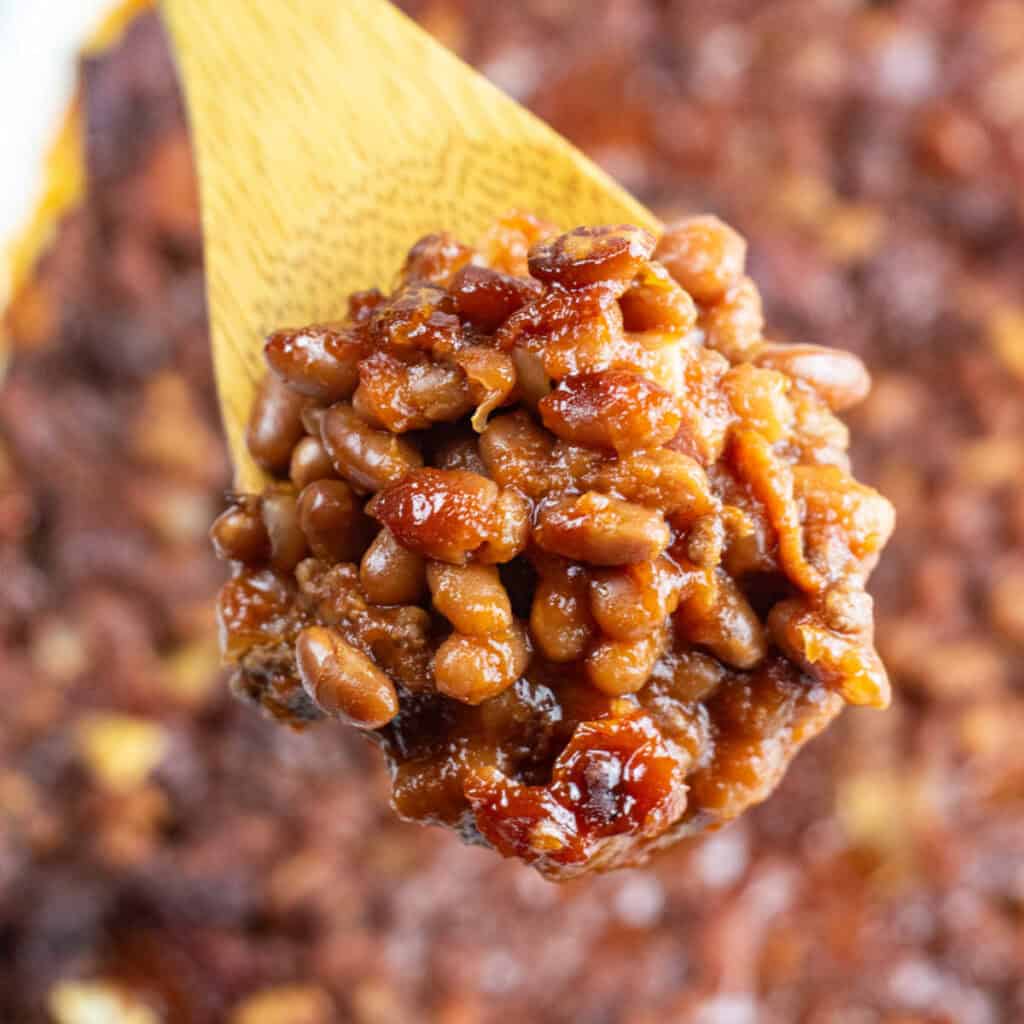 A scoop of baked beans on a wooden spoon